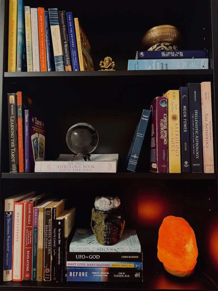 Personal bookshelf displaying spiritual and astrology books, a Himalayan salt lamp, and a crystal ball, representing holistic self-care for anxiety.